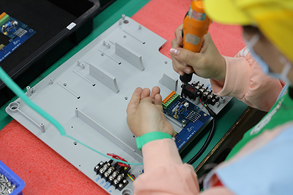 box build operator with screw driver assembling pcb onto plastics